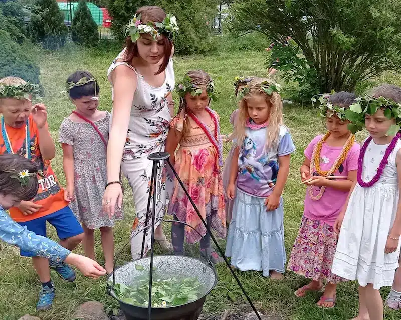 malá děvčátka s paní učitelkou u bylinného čaje v kotlíku na zahradě na Sv. Jána